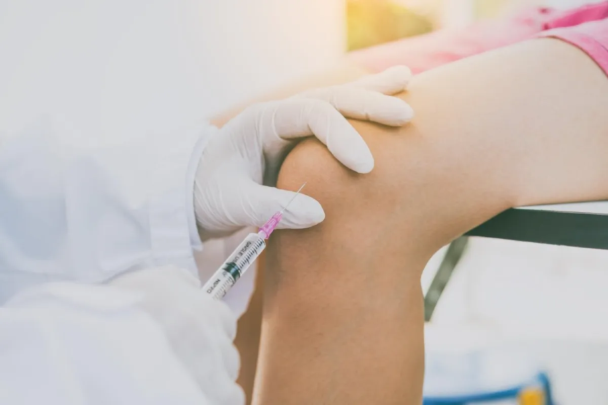 Gloved hands giving an injection into a patient knee