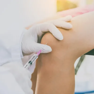 Clinician giving an injection into a patient knee